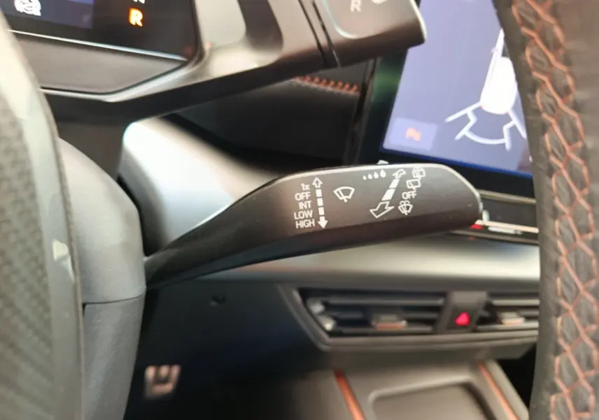 Gros plan sur la commande d’essuie-glace à gauche du volant dans l’habitacle gris foncé du CUPRA Born 230ch 2023.