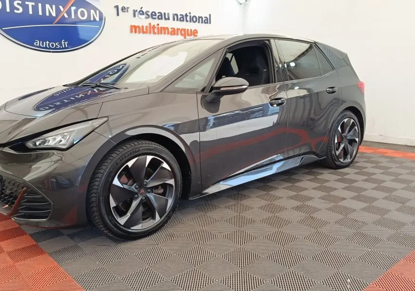 Vue 3/4 avant droit d'une CUPRA Born 230ch gris foncé électrique, avec jantes distinctives et intérieur visible.