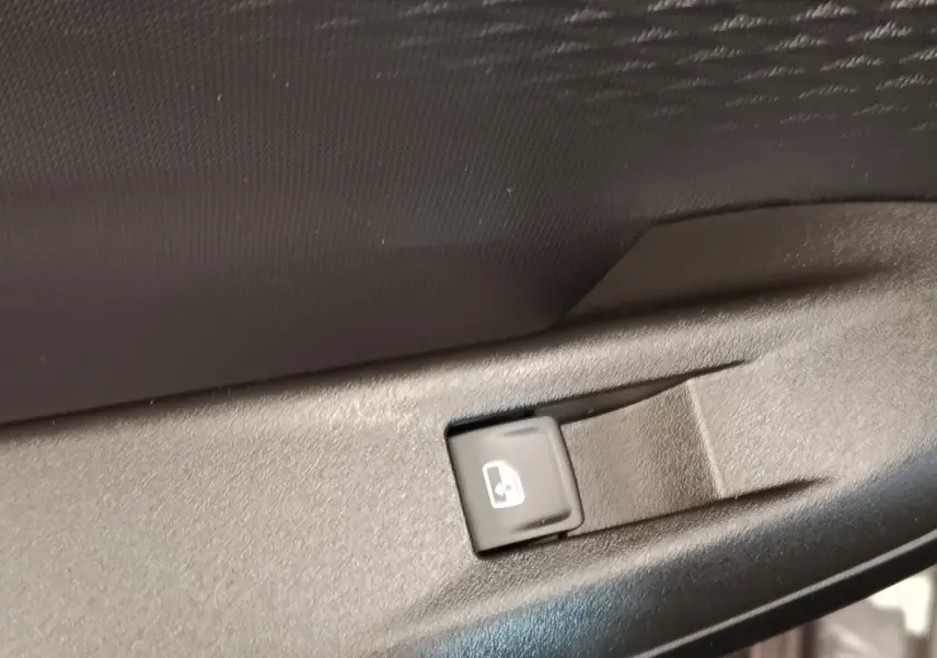 Bouton de commande de lève-vitre électrique sur la porte intérieure d'une CUPRA BORN gris foncé, vue rapprochée.