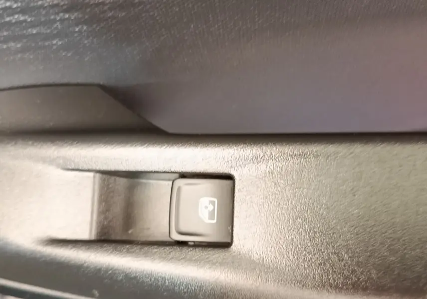 Bouton de commande de lève-vitre électrique sur panneau intérieur noir, détail du CUPRA Born 230ch gris foncé 2023.