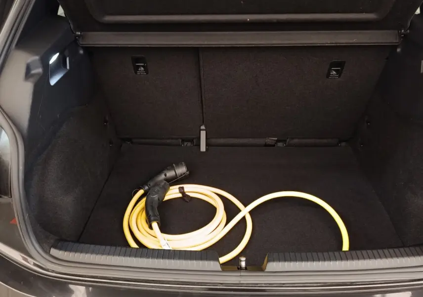 Coffre ouvert d'une CUPRA Born gris foncé avec câble de charge électrique jaune enroulé à l'intérieur.