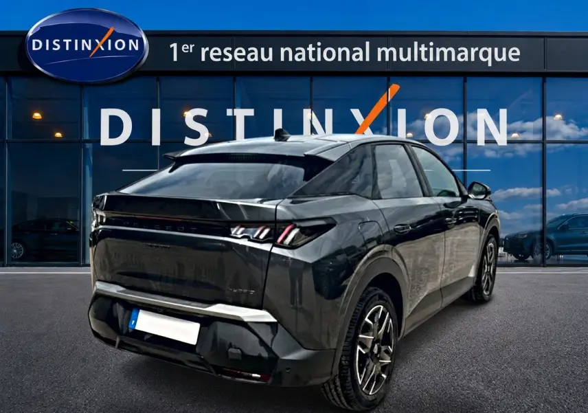 Vue 3/4 arrière droite du Peugeot 3008 gris titane avec feux LED et jantes alliage devant un showroom Distinxion.