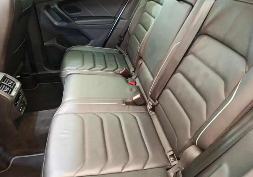 Vue latérale intérieure des sièges arrière en cuir noir du Volkswagen Tiguan 1.4 eHybrid 2023, avec ceintures et aérateurs.