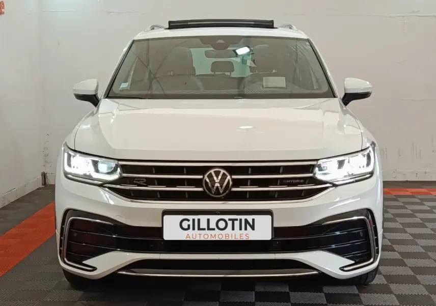 Volkswagen Tiguan 1.4 eHybrid blanc vu de face, phares LED allumés et calandre R-Line distinctive.