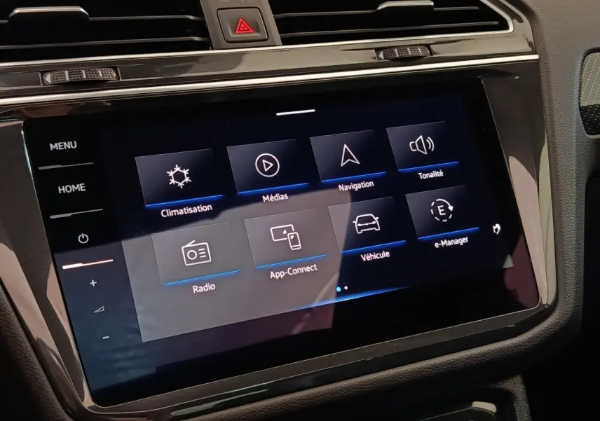 Écran tactile central du tableau de bord du Volkswagen Tiguan blanc 2023 affichant les menus climatisation, médias et navigation.