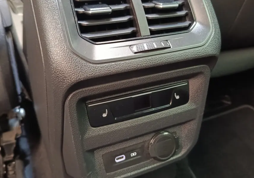 Détail intérieur du Volkswagen Tiguan blanc 2023 montrant la ventilation arrière et les commandes de sièges chauffants.