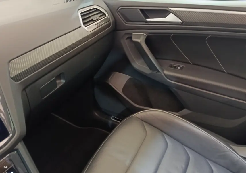 Vue intérieure côté passager du Volkswagen Tiguan 1.4 eHybrid 2023, avec siège cuir noir et garnitures carbone.