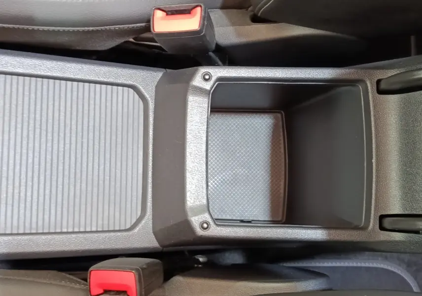 Vue plongeante sur le rangement central noir entre les sièges avant du Volkswagen Tiguan blanc 2023 hybride rechargeable.