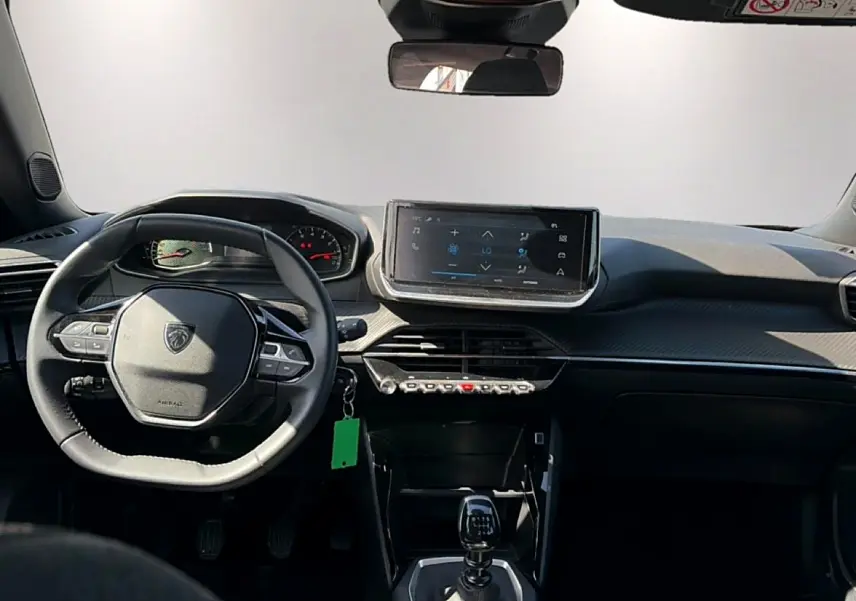 Vue intérieure frontale du tableau de bord et volant du Peugeot 2008 gris, avec écran tactile et levier de vitesse manuel.