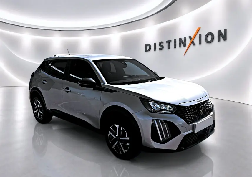 Peugeot 2008 gris en 3/4 avant droit, avec calandre noire et phares LED, dans un showroom lumineux.