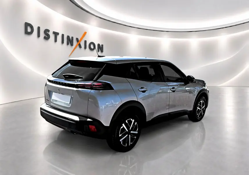Peugeot 2008 gris en 3/4 arrière droit dans un showroom lumineux avec jantes noires et toit noir.