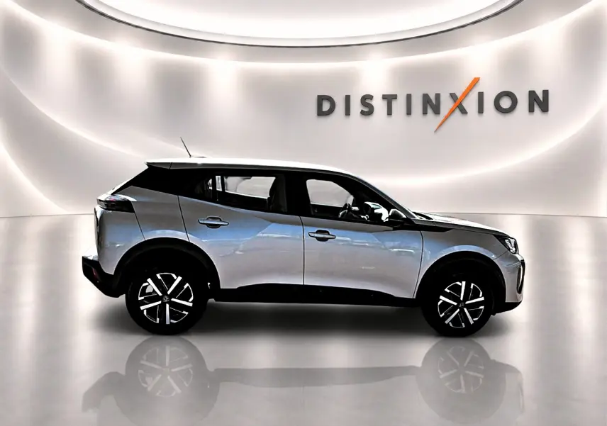 Profil droit du Peugeot 2008 gris 2025 avec toit noir et jantes distinctives en studio lumineux.