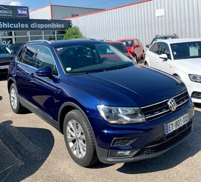 Volkswagen Tiguan bleu 3/4 avant droit, version 2.0 TDI 150ch confortline business de 2018, en extérieur sur parking.