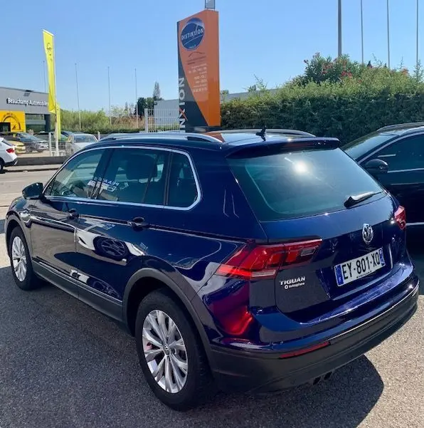 Volkswagen Tiguan bleu foncé vue 3/4 arrière droit, avec badge 2.0 TDI et toit ouvrant visible.