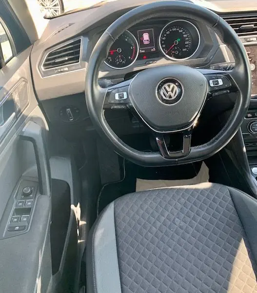Vue intérieure du volant et tableau de bord du Volkswagen Tiguan 2018, siège avant gris avec surpiqûres, commandes au volant visibles.