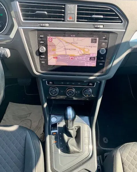 Vue intérieure centrée sur la console centrale du Volkswagen Tiguan 2018 bleu, avec écran tactile et levier de boîte auto DSG7.