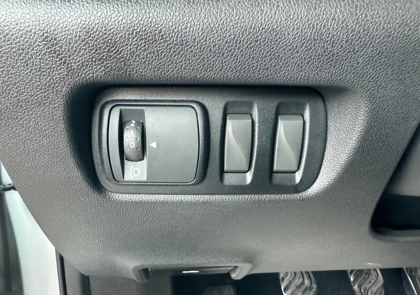 Gros plan sur les commandes de réglage des phares et des rétroviseurs côté conducteur du Renault Kadjar gris.