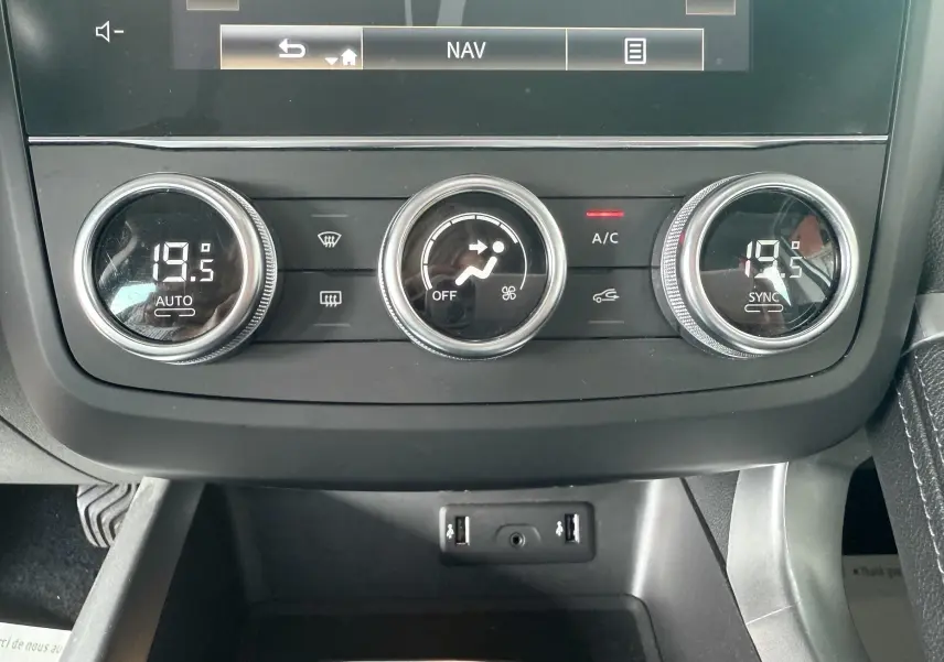 Vue rapprochée de la console centrale du Renault Kadjar gris, avec commandes de climatisation et ports USB visibles.