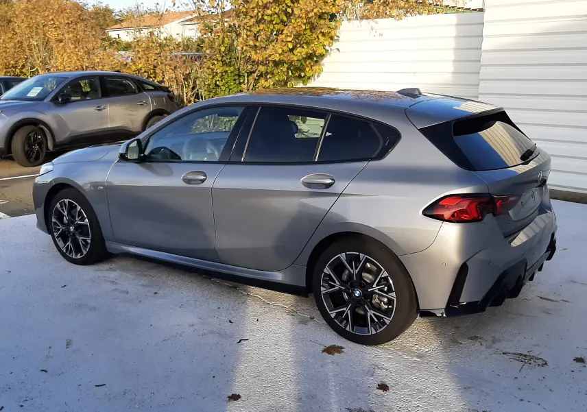 BMW Série 1 gris Skyscraper vue 3/4 arrière côté gauche, avec jantes alliage 18'' style 975M bicolores.