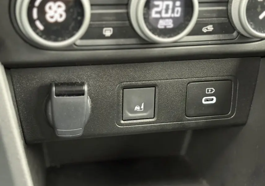 Gros plan sur les commandes du tableau de bord de la Dacia Sandero Stepway Bleu Iron, avec bouton d'aide au démarrage en côte et prise USB-C.