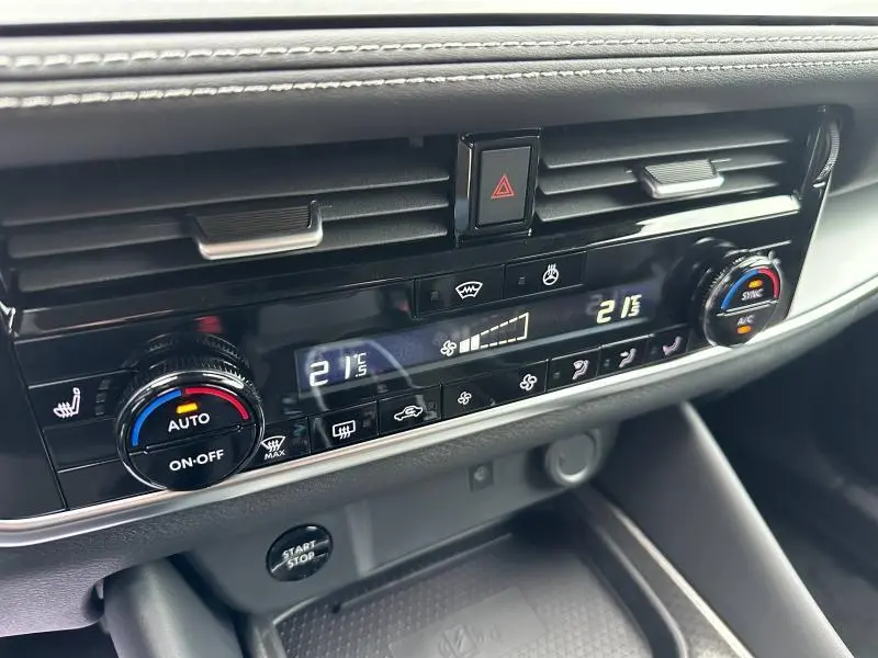 Gros plan sur la console centrale du Nissan Qashqai Hybrid e-POWER 2025, avec commandes climatisation digitales et boutons noirs.