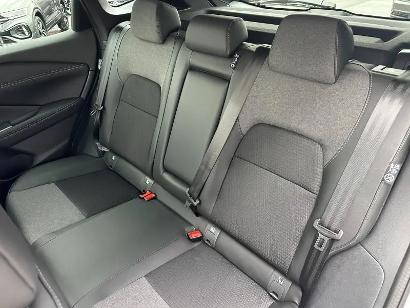 Vue intérieure sur les sièges arrière du Nissan Qashqai Hybrid e-POWER 2025, tissu gris avec ceintures de sécurité visibles.