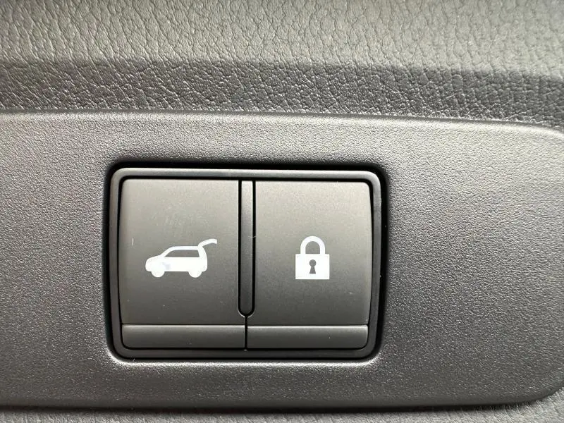 Boutons intérieurs de déverrouillage du coffre et de verrouillage centralisée sur Nissan Qashqai Hybrid e-POWER 2025, vue rapprochée.