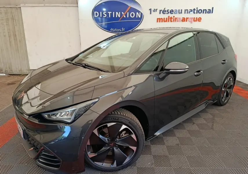 Vue 3/4 avant droit d'une CUPRA BORN gris foncé avec jantes noires et logo distinctif sur calandre.