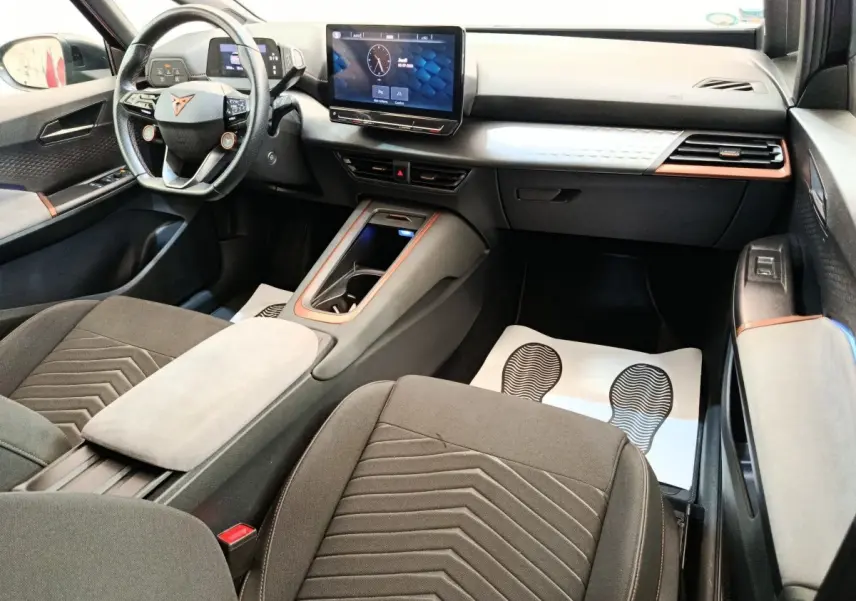 Intérieur du CUPRA BORN 230ch vu côté passager, avec tableau de bord noir et gris clair, volant cuir et écran tactile central.