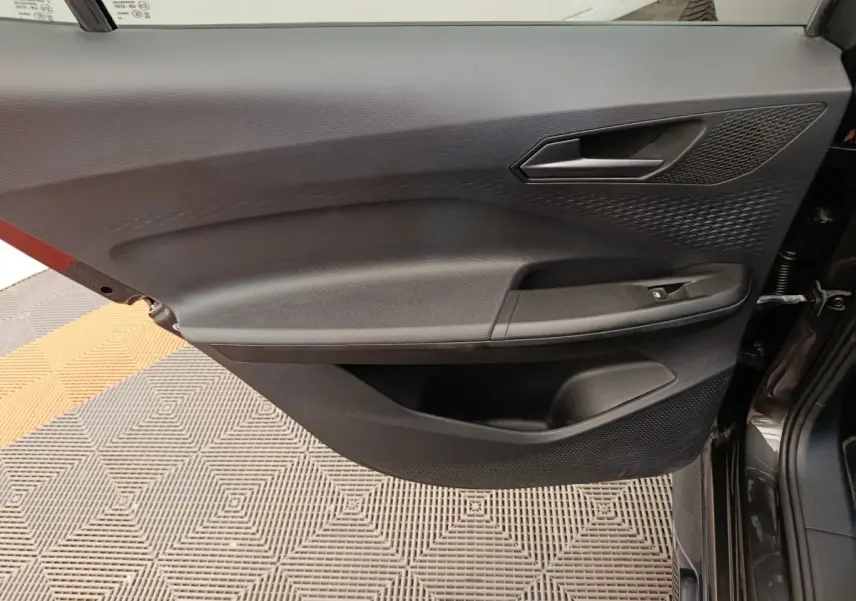 Vue latérale du panneau de porte avant droit gris foncé du CUPRA BORN 230ch avec poignée et commande de vitre électrique.