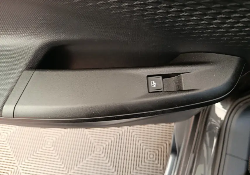 Détail de la commande de lève-vitre électrique sur la porte côté conducteur d'une CUPRA Born gris foncé.
