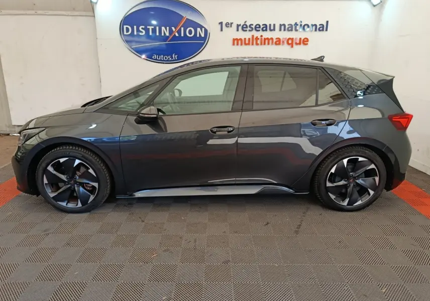Vue de profil côté gauche d'une CUPRA BORN 230ch gris foncé avec jantes noires et toit noir brillant.