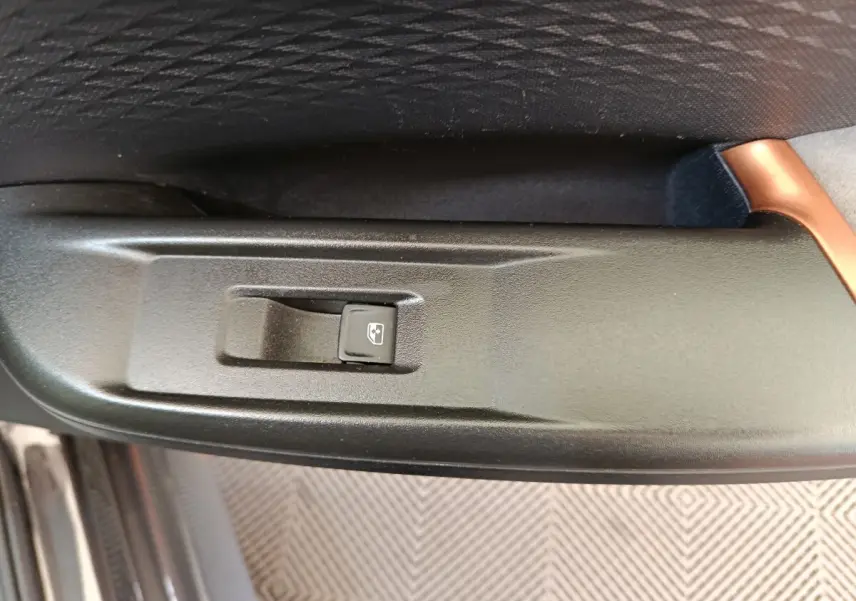 Gros plan sur l'interrupteur de lève-vitre électrique côté conducteur dans l'habitacle noir du CUPRA Born 2023.