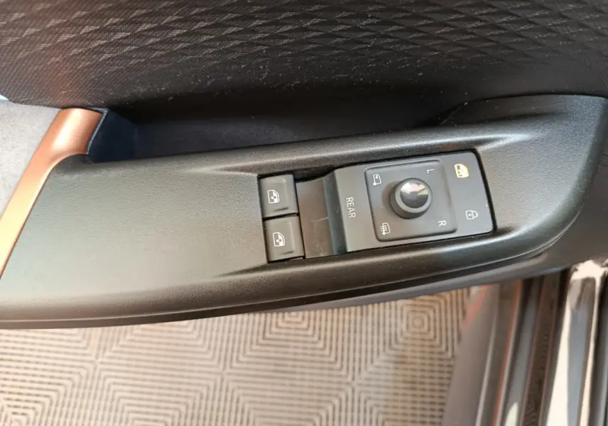 Gros plan sur les commandes de réglage des rétroviseurs et des vitres côté conducteur d'une CUPRA BORN gris foncé.