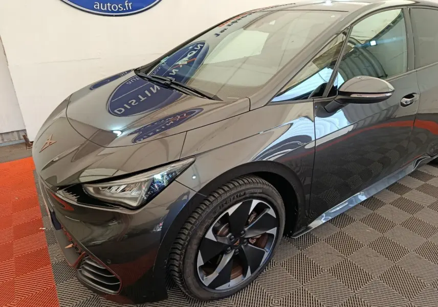 Vue 3/4 avant droit d'une CUPRA BORN gris foncé électrique avec jantes noires et détails orange sur le bouclier avant.
