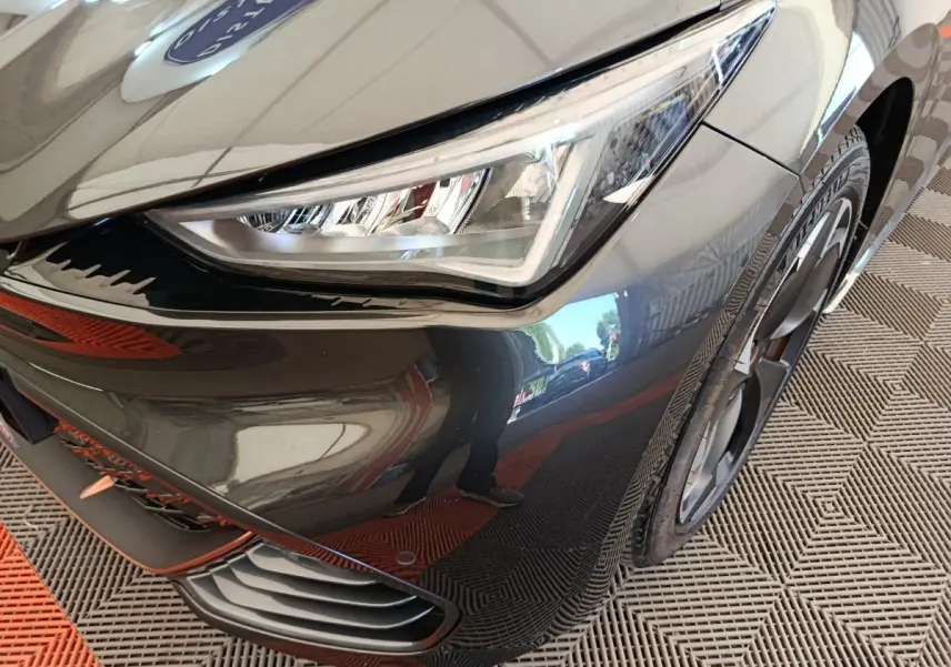 Gros plan sur l'avant droit gris foncé du CUPRA BORN 230ch, mettant en valeur le phare LED et la jante noire.