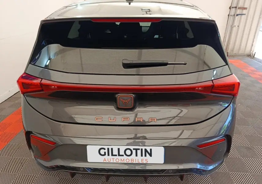 Vue arrière d'une CUPRA BORN gris foncé avec feux arrière LED reliés et logo CUPRA central lumineux.