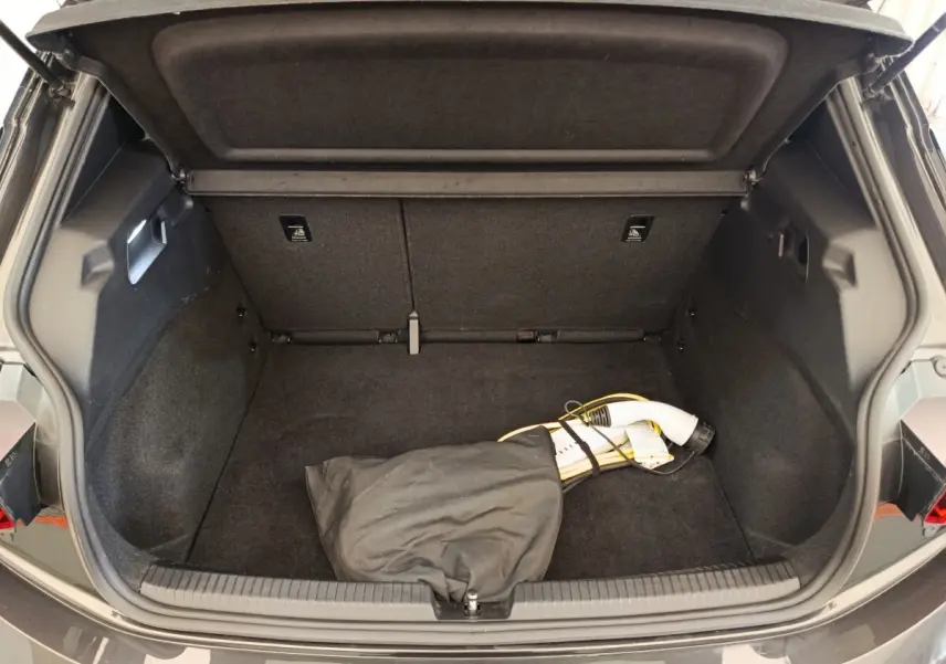 Coffre ouvert d'une CUPRA Born gris foncé, vue arrière, avec câble de charge électrique visible à l'intérieur.