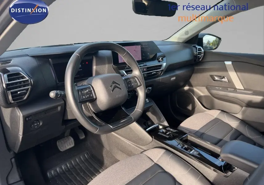 Intérieur de la Citroën C4 2023 en gris, vue côté conducteur montrant tableau de bord et volant multifonction.