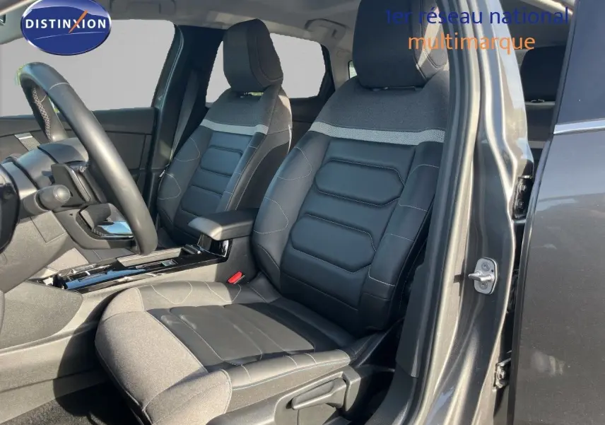 Vue intérieure côté conducteur de la Citroën C4 2023 gris, sièges en tissu et cuir noir avec détails gris.