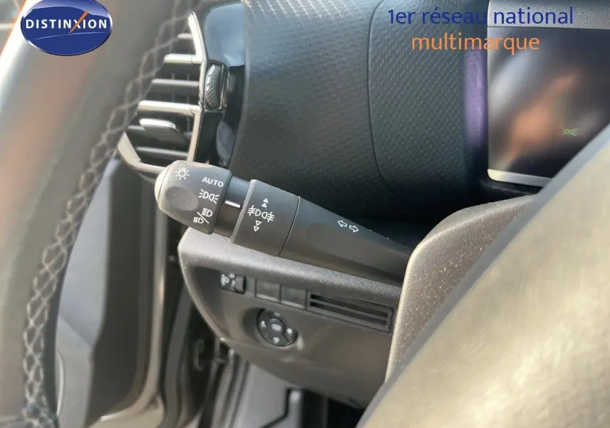 Vue intérieure côté conducteur du commodo d’éclairage et clignotants sur Citroën C4 gris 2023.