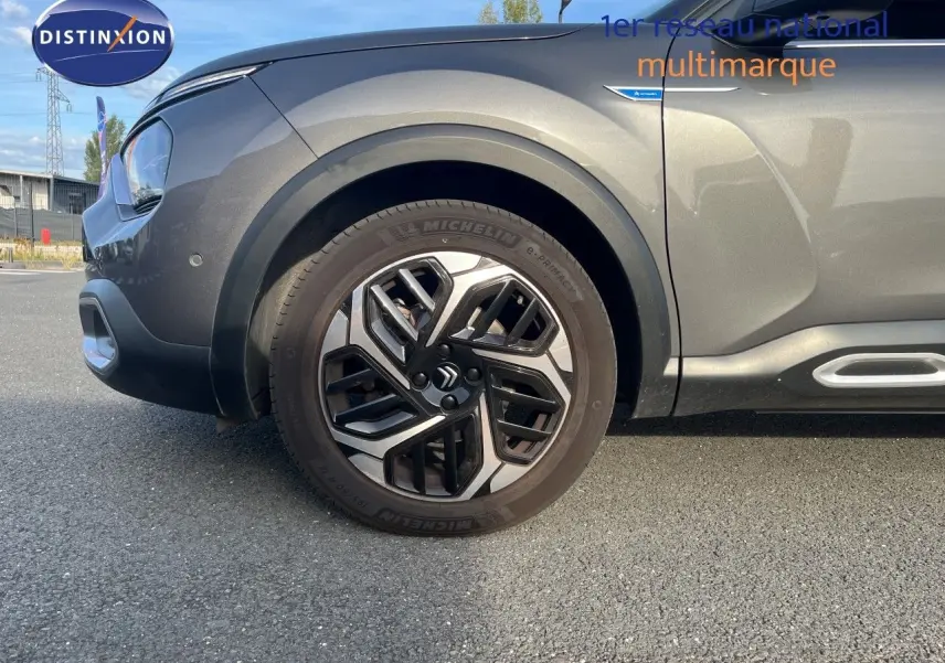 Vue latérale gauche rapprochée sur la roue avant et la carrosserie gris métallisé du Citroën C4 2023.