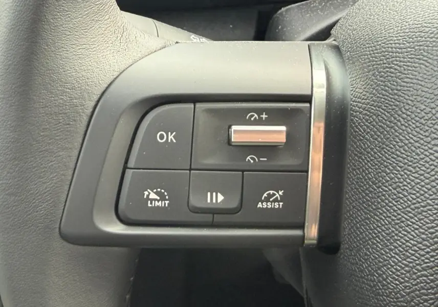 Gros plan sur les commandes noires du volant à gauche de la Citroën C4 électrique blanche 2024.