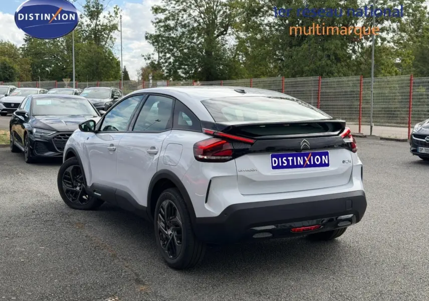 Vue 3/4 arrière droite d'une Citroën C4 électrique blanche avec jantes noires et feux arrière LED distinctifs.