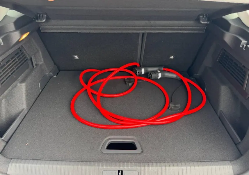 Coffre ouvert d'une Citroën C4 électrique blanche, vue de dessus, avec câble de recharge rouge enroulé.