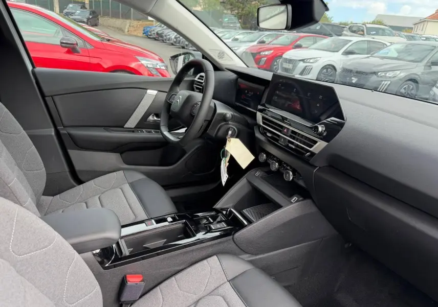 Vue intérieure côté conducteur du Citroën C4 2024 électrique, montrant sièges gris et tableau de bord moderne.