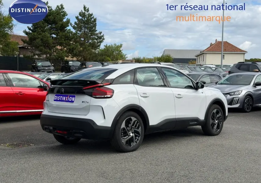 Vue 3/4 arrière droite d'une Citroën C4 électrique blanche avec toit noir et jantes distinctives.