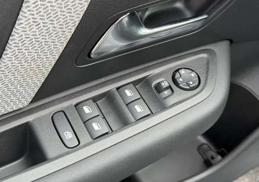 Gros plan sur la commande des vitres et rétroviseurs côté conducteur d'une Citroën C4 électrique blanche 2024.
