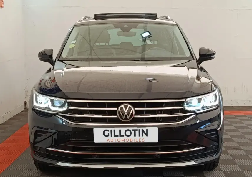 Volkswagen Tiguan noir 2021 vue de face avec phares LED allumés et calandre chromée visible.