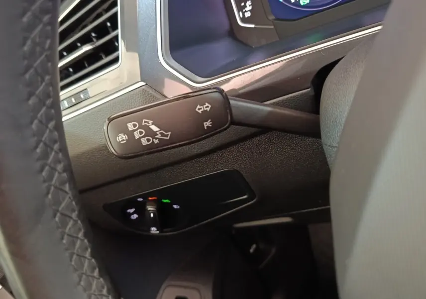 Gros plan sur la manette de clignotants et le tableau de bord numérique du Volkswagen Tiguan noir, intérieur conducteur.